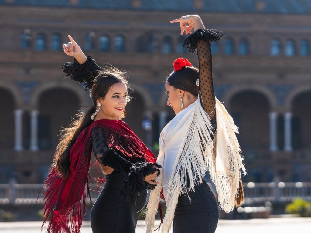 mujeres bailando sevillanas en una plaza
